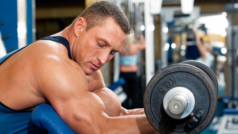 Male bodybuilder performs a preacher curl.