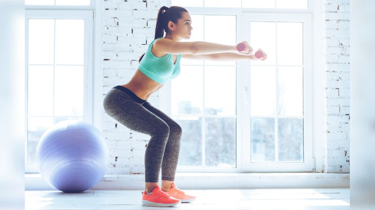 A person doing a squat with handweights.