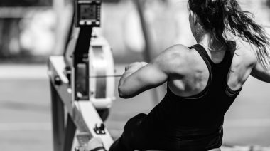 Muscular person with long hair using rowing machine