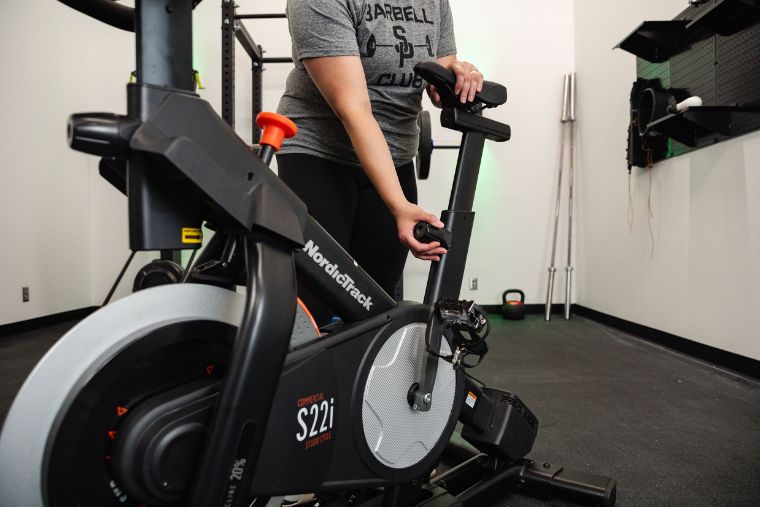 A woman adjusting the seat height on the NordicTrack S22i Studio Bike