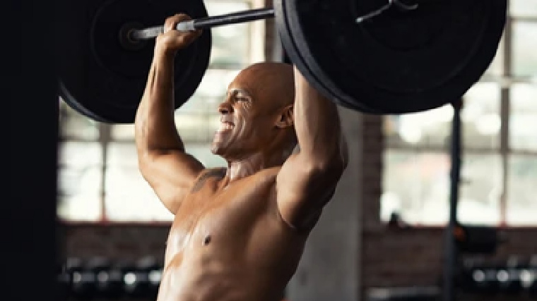 muscular person in gym straining while pressing barbell