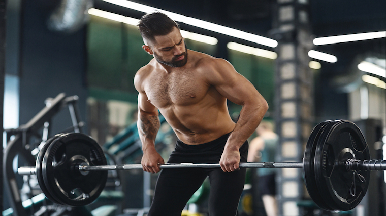 muscular person in gym rowing barbell