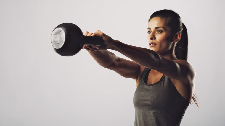 Person in grey tank top performing kettlebell swing