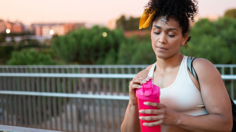 muscular person outdoors drinking protein shake