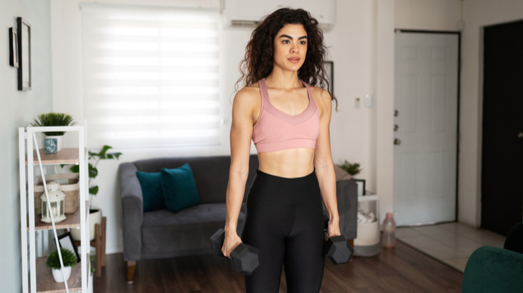 Woman in home gym standing holding dumbbells