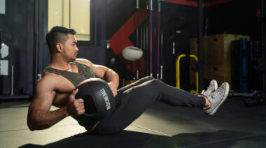 Man on ground performing ab exercise with medicine ball