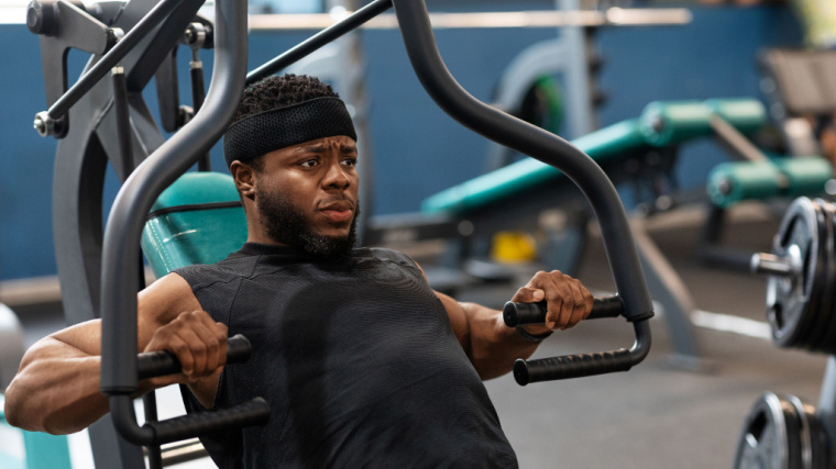 muscular person using chest press machine