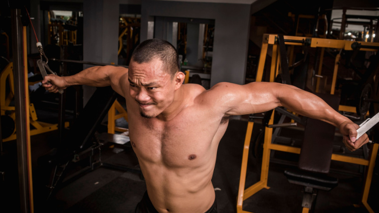 muscular person doing chest exercise with cables