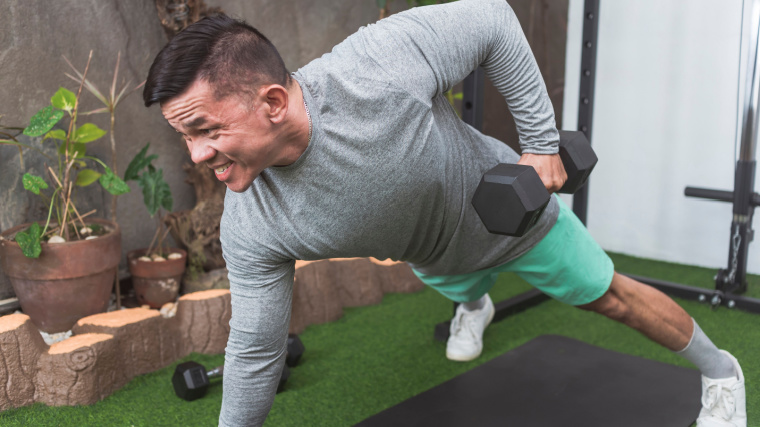 muscular person in outdoor gym doing dumbbell row