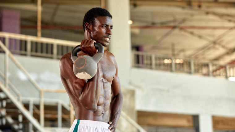 muscular person outdoors holding kettlebell