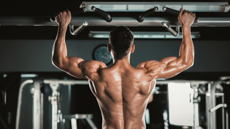 Bodybuilder performing pull-ups in gym