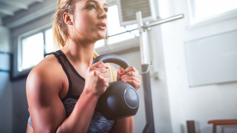 Long-haired person in gym holding kettlebell