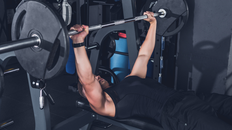 Man in gym performing barbell bench press