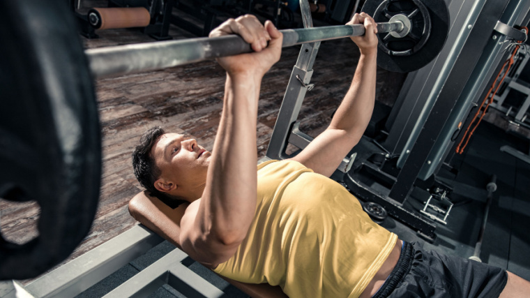 person in gym doing bench press